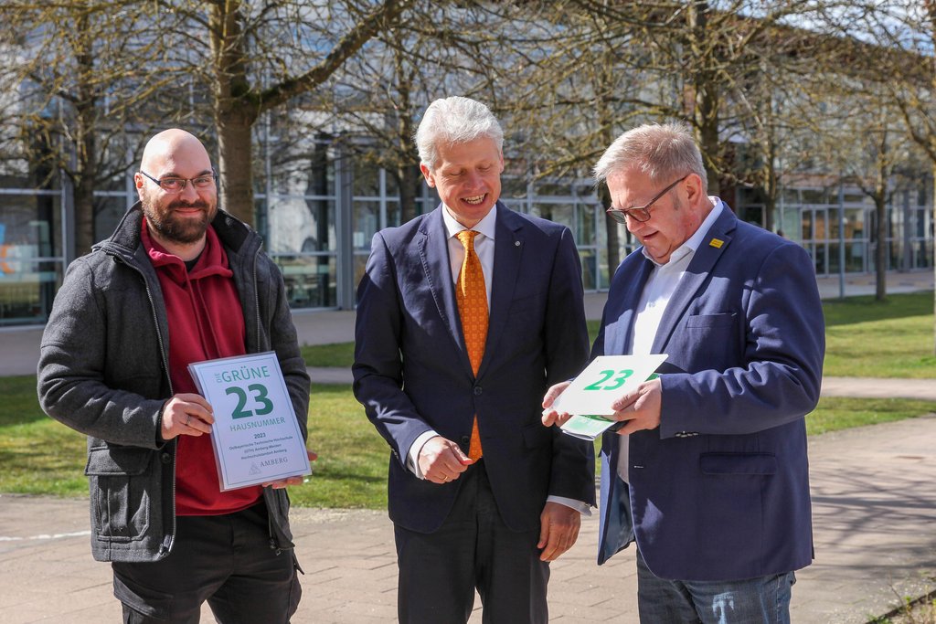 Das Foto zeigt Christoph Dereser, Klimaschutzmanager Stadt Amberg, Hochschulpräsident Prof. Dr. Clemens Bulitta und Martin J. Preuß, Bürgermeister Stadt Amberg, mit dem Schild „Grüne Hausnummer“.