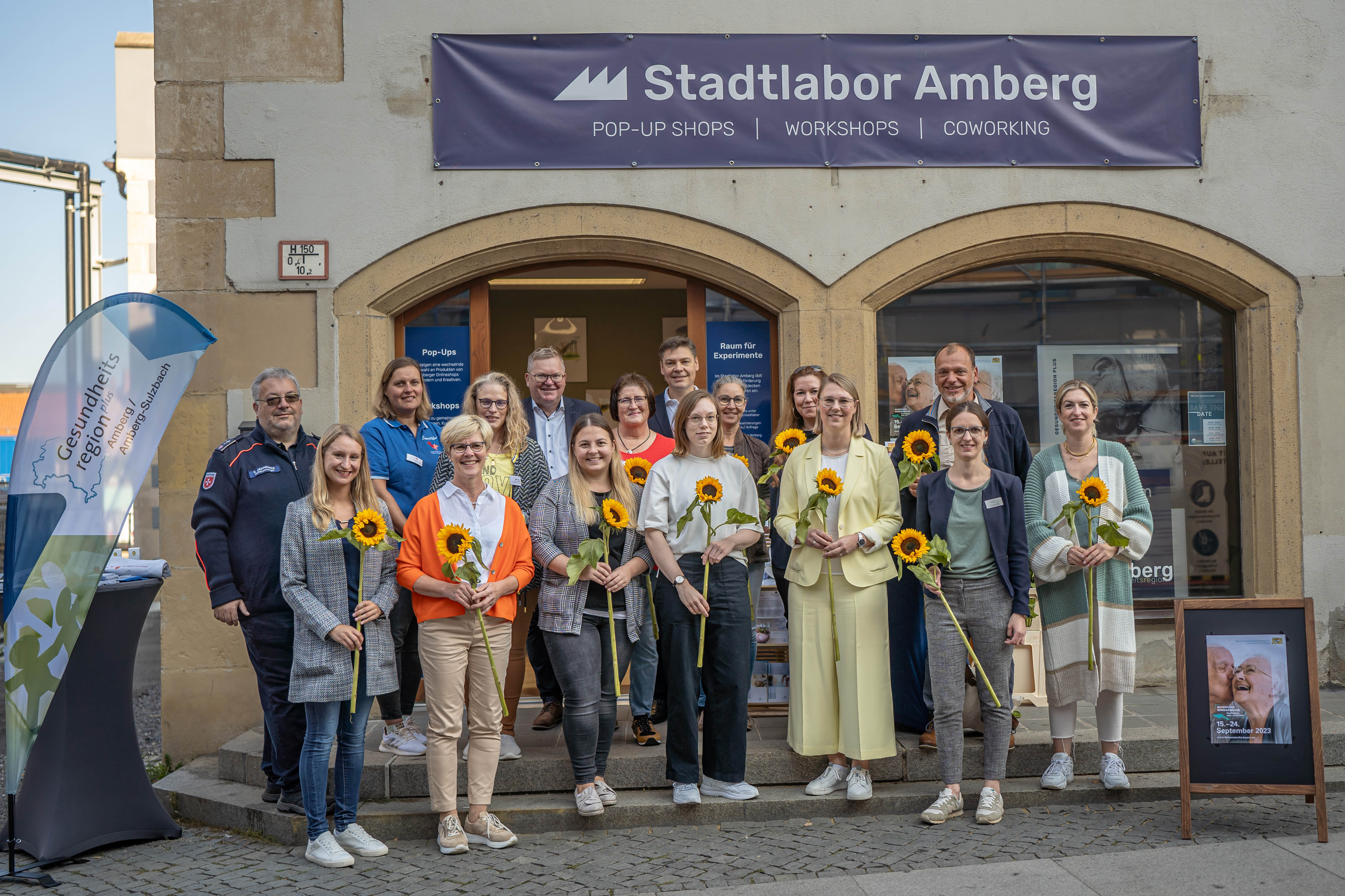 Das Gruppenfoto zeigt die Beteiligten bei der Eröffnung der Bayerischen Demenzwochen vor dem Stadtlabor Amberg mit Oberbürgermeister Michael Cerny