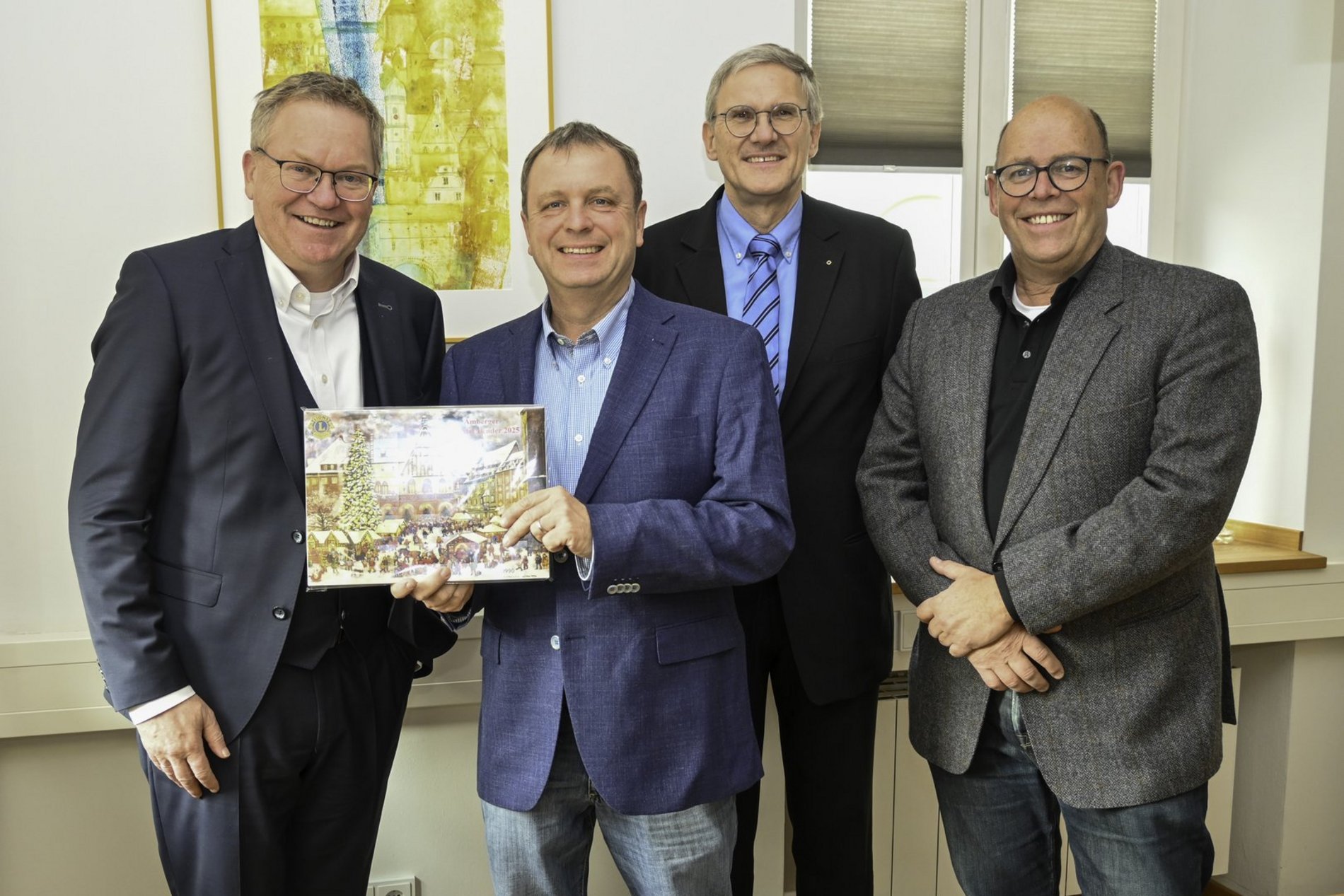 Das Foto zeigt, wie Oberbürgermeister Michael Cerny traditionell den ersten Adventskalender des Amberger Lions-Clubs von Andreas Herrmann, Vorsitzender des Lions-Hilfswerks, Lions-Vize-Präsident Jean-Paul Op de Laak und Lions-Sekretär Helmut Weigl überreicht bekommt.