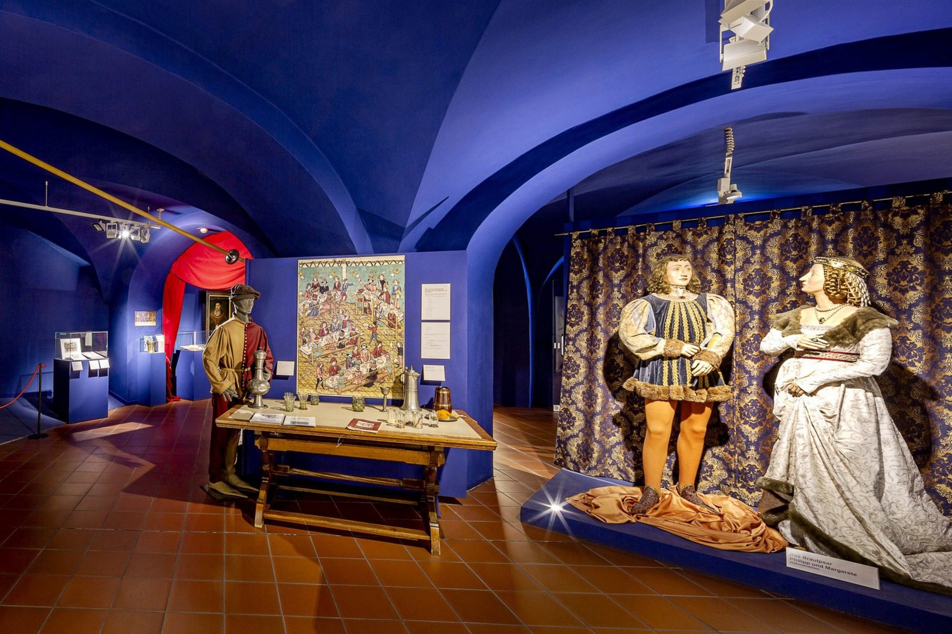 Das Foto zeigt einen Teil der Dauerausstellung Stadtgeschichte mit historischen Gewändern und Alltagsgegenständen aus dem Mittelalter.
