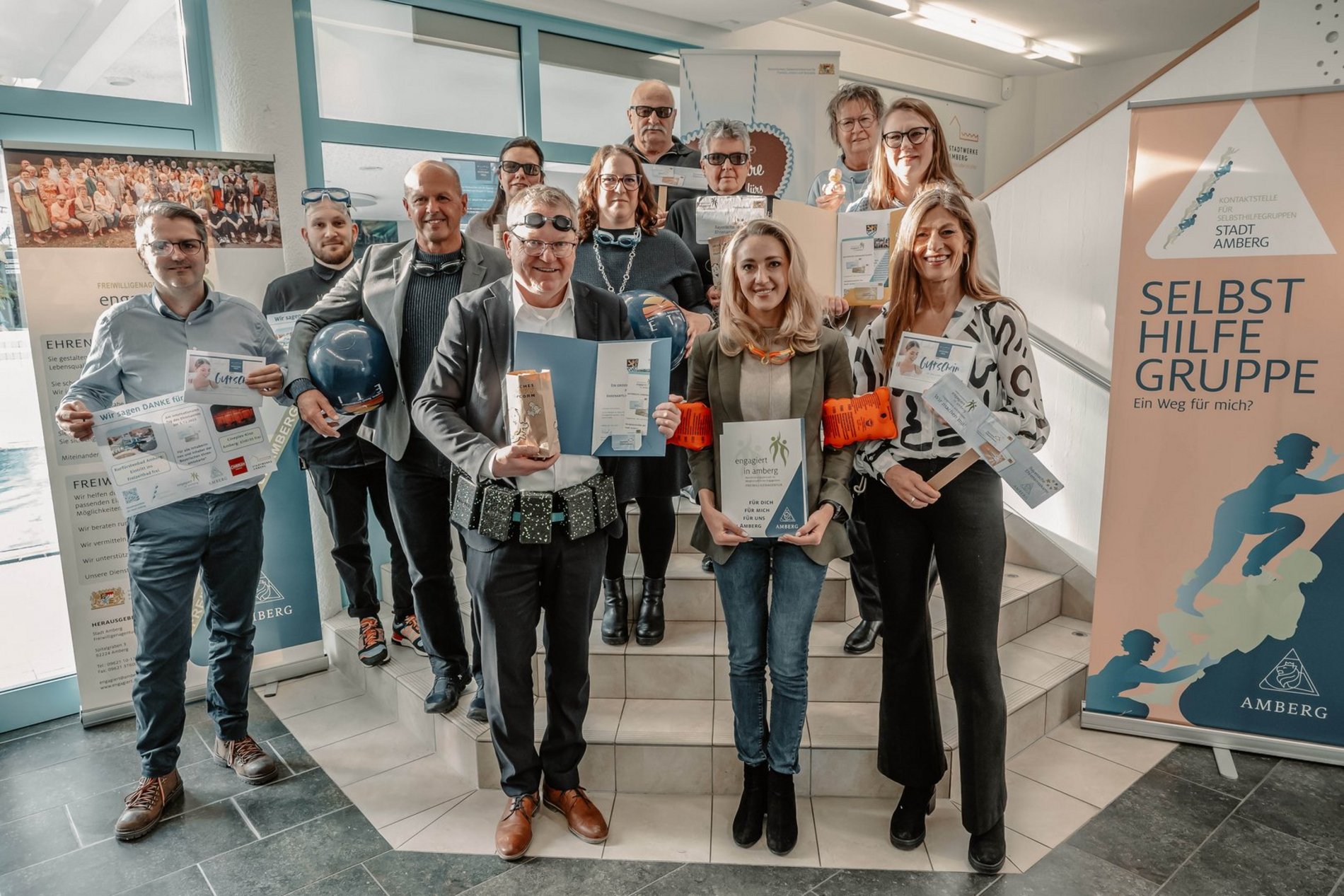 Das Foto zeigt die Beteiligten von der Stadt Amberg, aus der Freiwilligenagentur, den Stadtwerken und dem Cineplexkino. Sie stellten mit Schwimmutensilien und Popkorn im Kurfürstenband die Aktionen rund um den Internationalen Tag des Ehrenamts vor.