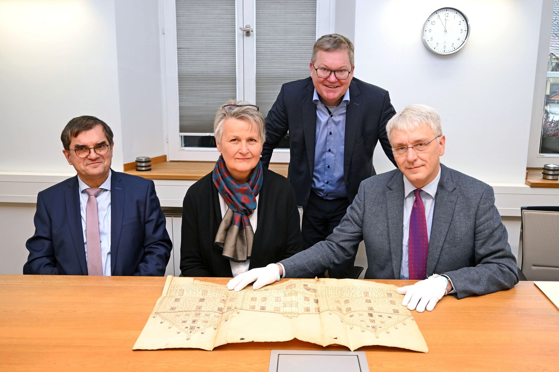 Landgerichtspräsident Dr. Stefan Täschner, die Leiterin des Staatsarchivs Dr. Maria Rita Sagstetter, Stadtarchivar Dr. Andreas Erb und Oberbürgermeister Michael Cerny bei der Begutachtung der aus dem 16. Jahrhundert stammenden Zeichnung der Regierungskanzlei, die einst die Vorgängerbehörde des Staatsarchivs und jetzt das Landgericht beherbergt. 