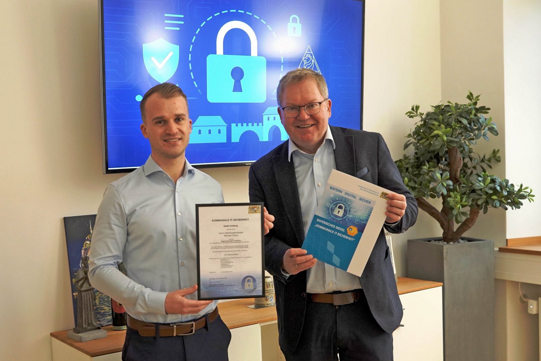 Das Foto zeigt den Oberbürgermeister Michael Cerny und den städtischen Informationssicherheitsbeauftragten Johannes Dotzler mit der Urkunde