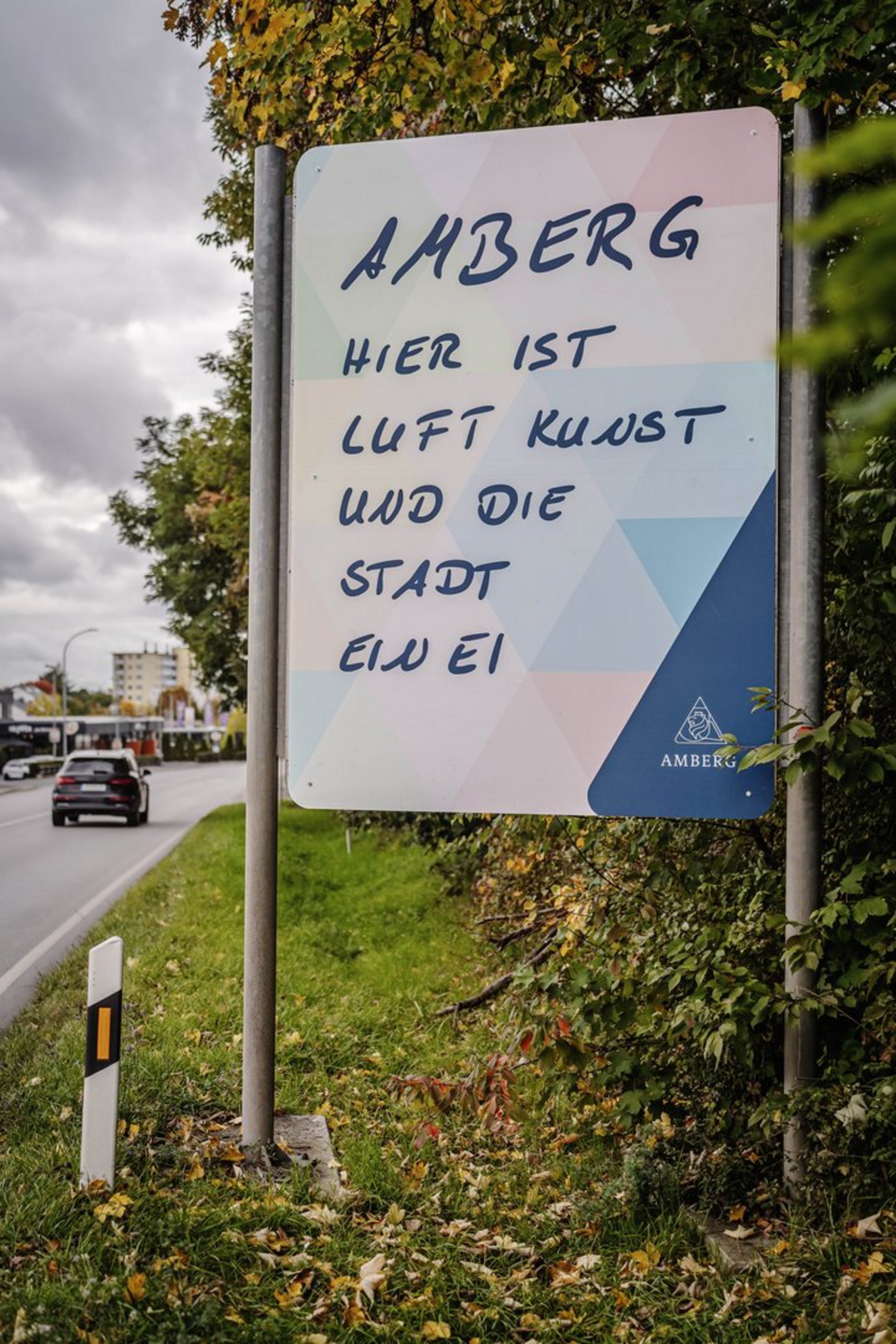 Das Foto zeigt die neue Stadteingangstafel in der Regensburger Straße mit dem Spruch „Amberg. Hier ist Luft Kunst und die Stadt ein Ei“.